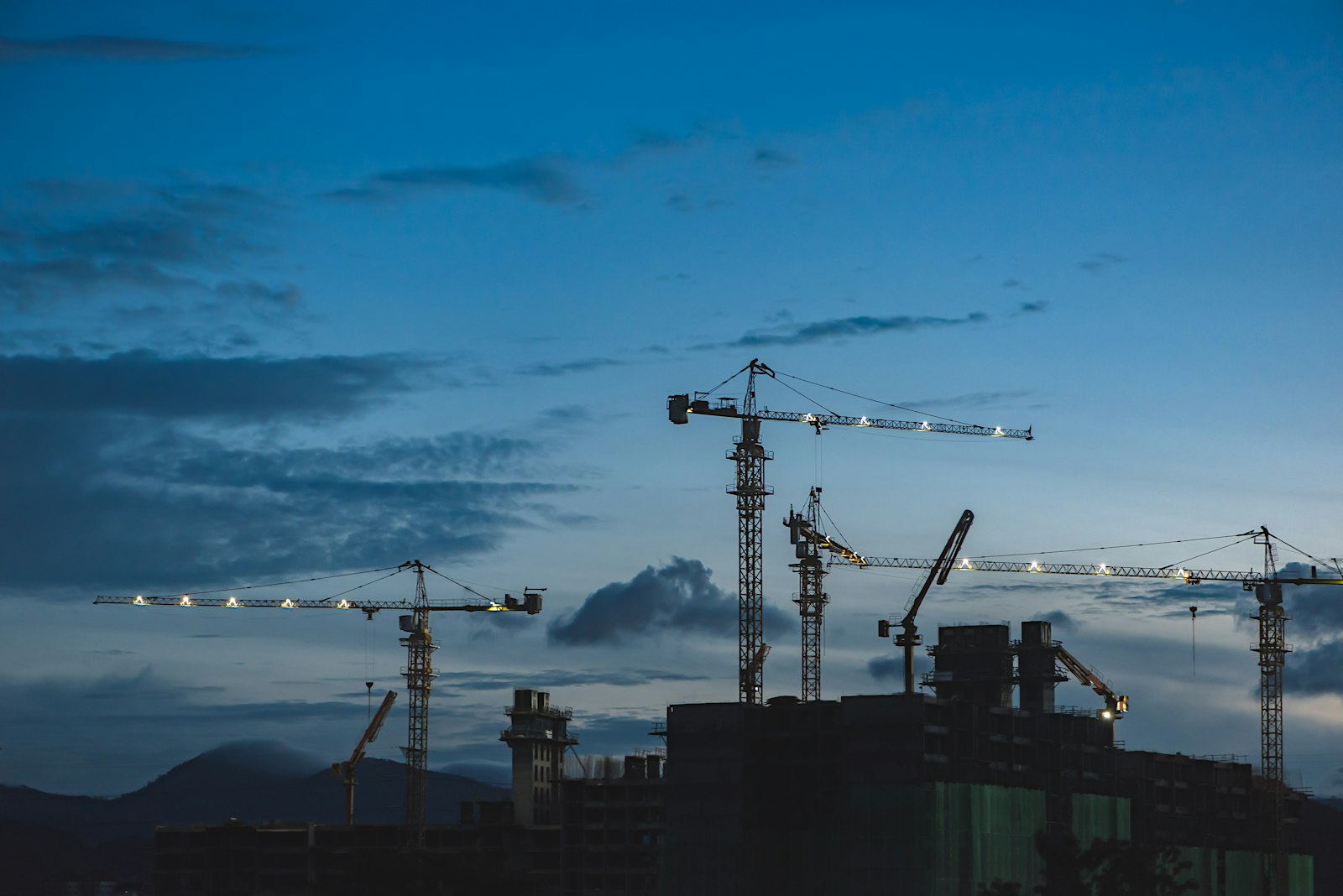 Construction cranes silhouetted against the evening sky at a building site