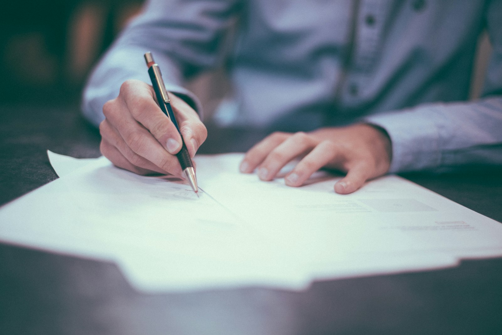 Close-up of a hand signing a property purchase agreement