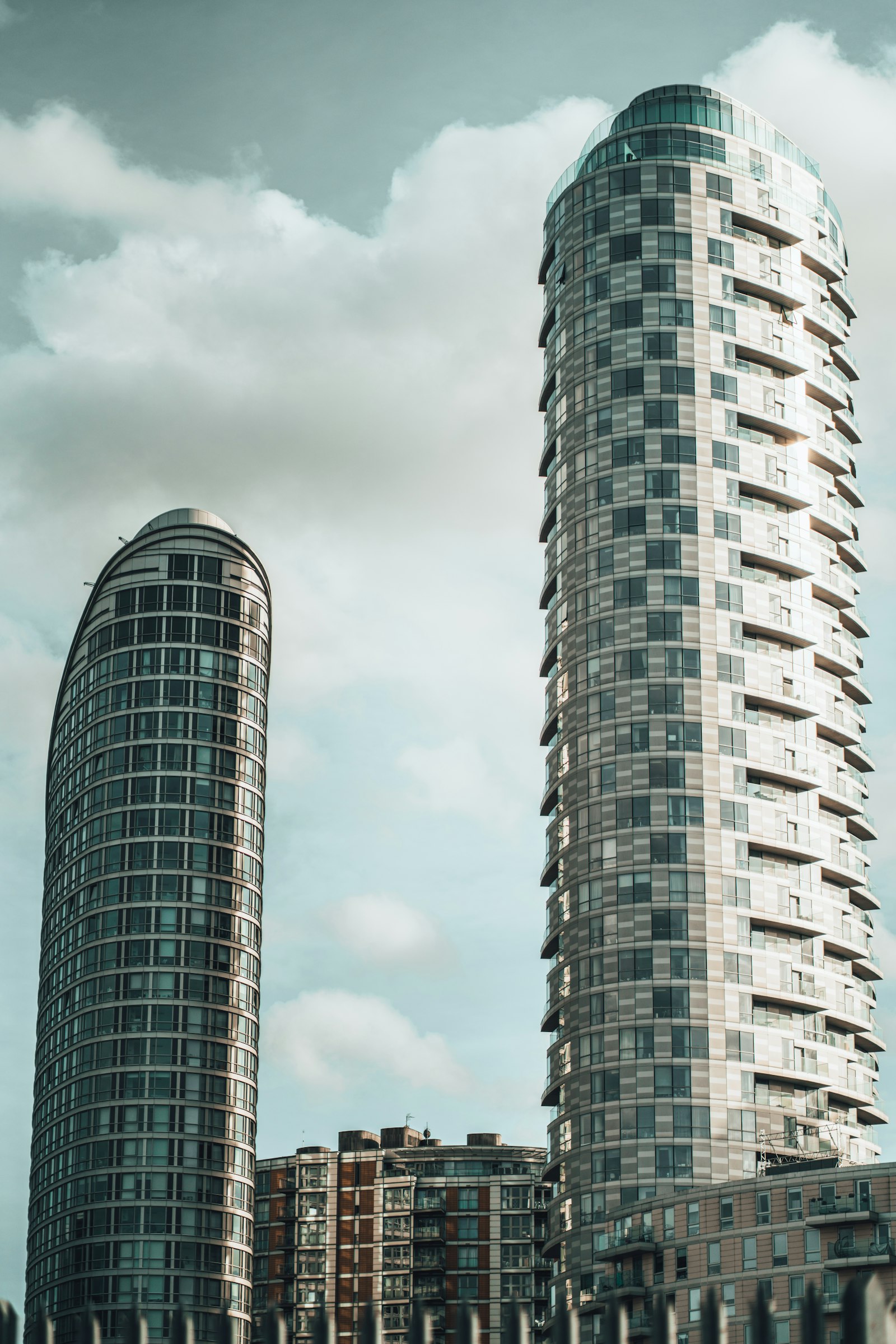 Two residential towers of different heights side by side against the sky
